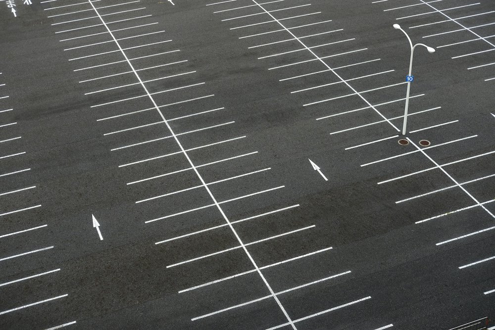 Parking en enrobé noir vu du dessus avec ses marquages blancs